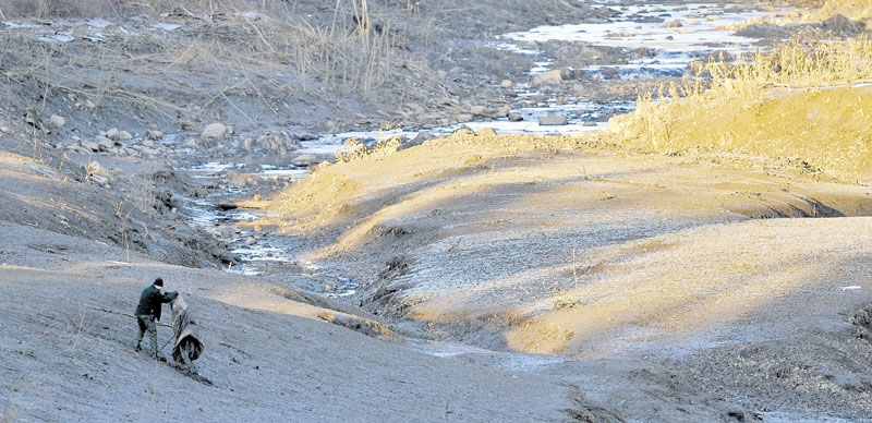 STILL LOOKING: A searcher scours the emptied river bed of the Messalonskee Stream along West River Road near the intersection of Kennedy Memorial Drive in Waterville Tuesday afternoon for Ayla Reynolds.