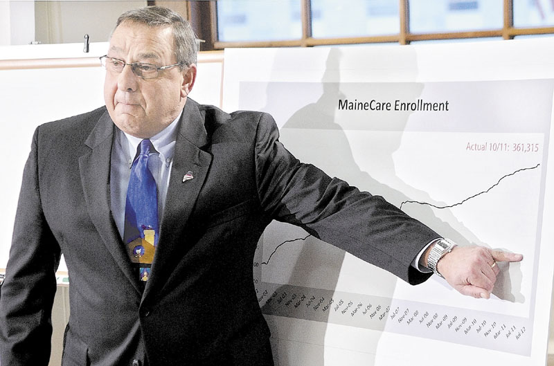 Gov. Paul LePage gestures at graph to show how much lower he'd like to see MaineCare enrollment numbers drop at a news conference Dec. 6 in Augusta.