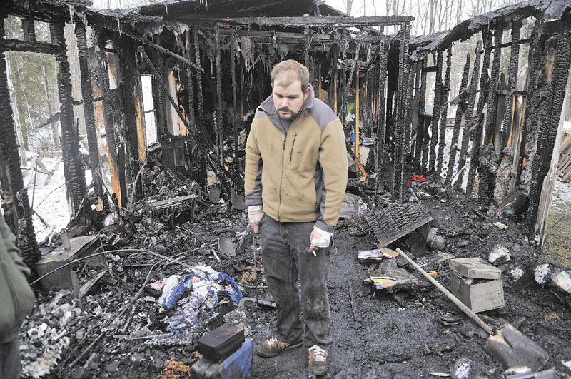 FIRE IN OAKLAND: Ryan Shuman stands in what used to be the living room of his family’s mobile home after a fire there early Tuesday morning in Oakland. Shuman barely made it out of the home alive and was taken by LifeFlight helicopter to a hospital in Bangor, where he was later released with burns to his hands, feet and back. On Tuesday afternoon, Shuman was using his bandages hands to salvage anything that wasn’t destroyed.