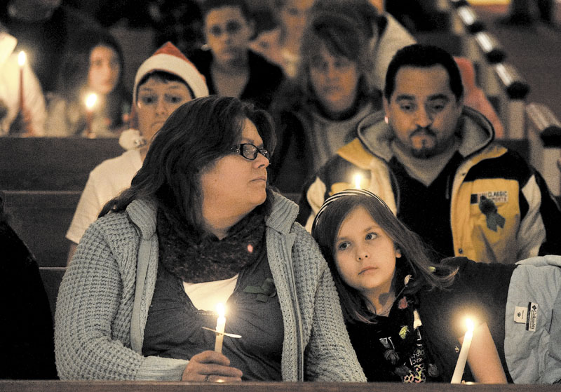 LIGHTS: Katherine McIntyre, left, sits with her daughter Noelle, 7, at a vigil for Ayla Reynolds organized by the Mainely Moms & Dads organization at the First Congregational Church in Waterville on Wednesday.