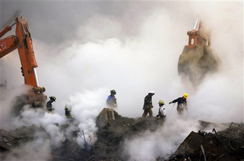 In this Oct. 11, 2001 file photo, firefighters make their way over the ruins of the World Trade Center through clouds of dust and smoke at ground zero in New York. More than 1,600 people suing over their exposure to World Trade Center dust must decide by Jan. 2 whether to keep fighting in court, or drop their lawsuits and apply for benefits from a government fund. (AP Photo/Stan Honda, Pool, File)
