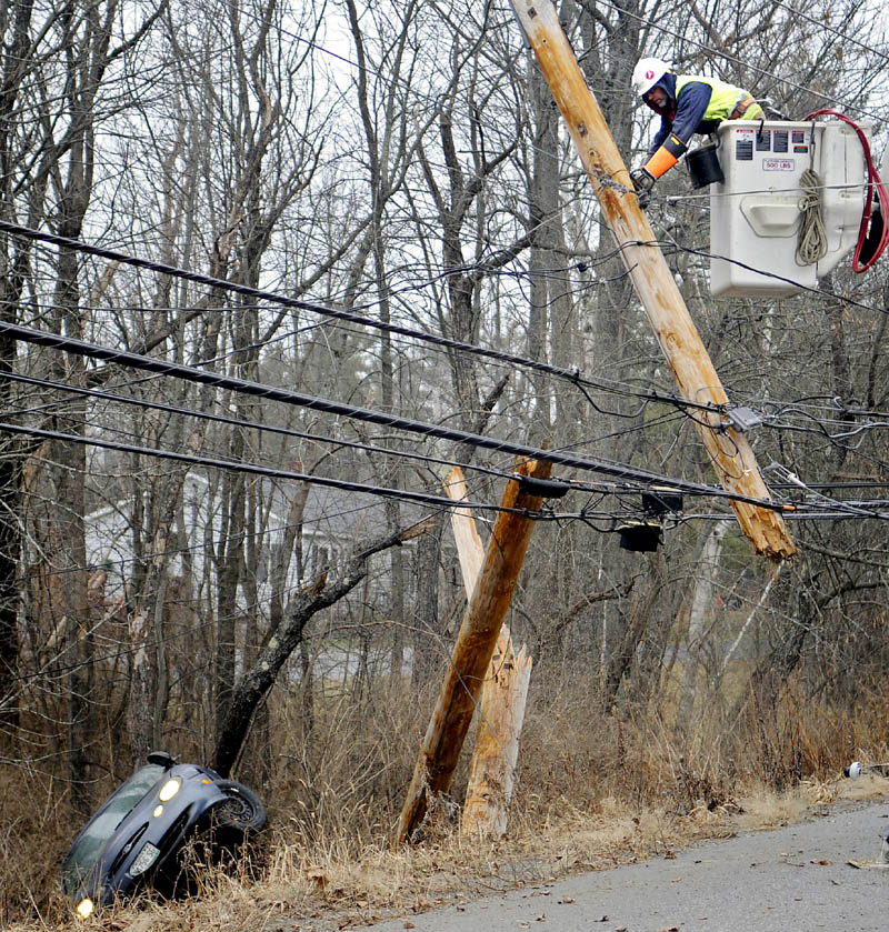 Central Maine Power lineman Ed Lake saws the top of a utility pole Wednesday morning after a car carrying two people snapped it, injuring both occupants, on the Churchill Road in Augusta. Several accidents were reported across Kennebec County due to black ice.