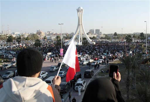 Bahrainis wave a flag and take photographs of protestors from a highway overpass overlooking the Pearl Monument centered on a main square in Manama, Bahrain, Tuesday Feb. 15, 2011. "The Protestor" was named Time's "Person of the Year". (AP Photo/Hasan Jamali)