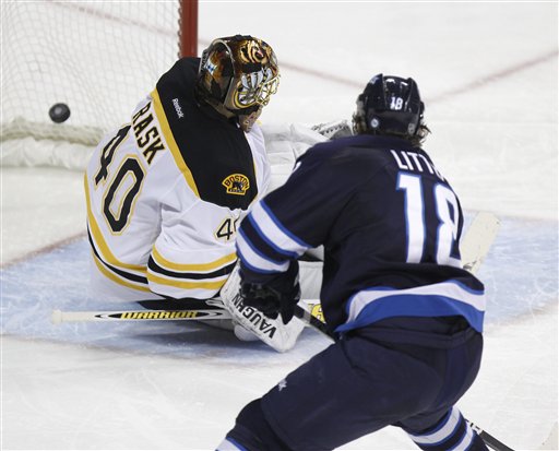 Winnipeg Jets' Bryan Little (18) puts the puck past Boston Bruins goaltender Tuukka Rask during the third period of an NHL hockey game in Winnipeg, Manitoba, on Tuesday. Canada Canadian sports play ice hockey game action competitive competition compete athletics athletic athlete NHL National Hockey League
