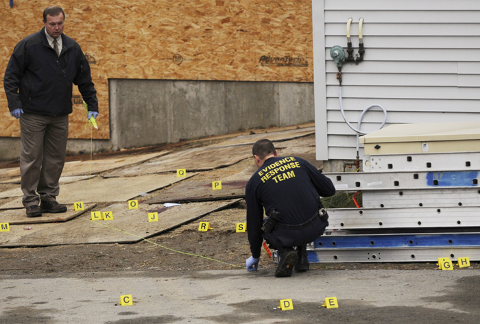 Maine State Police Trooper David Yankowski, left, and another member of the Evidence Response Team investigate the scene of a shooting behind the Hilltop Manor in Dover-Foxcroft on Tuesday. A sheriff's department dispatcher walked into a nursing home and fatally shot a maintenance worker before fleeing to nearby fairgrounds, where he was shot and killed by a state trooper.