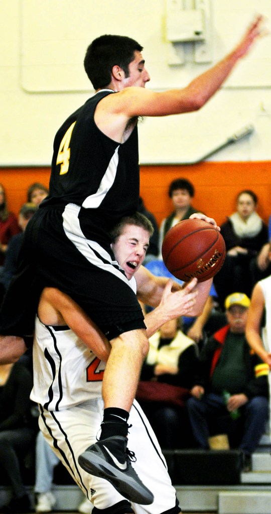 OVER THE TOP: Maranacook Community High School's Seth Miller lands Tuesday on the shoulders of Gardiner Area High School's Matt Hall during a basketball match up in Gardiner.