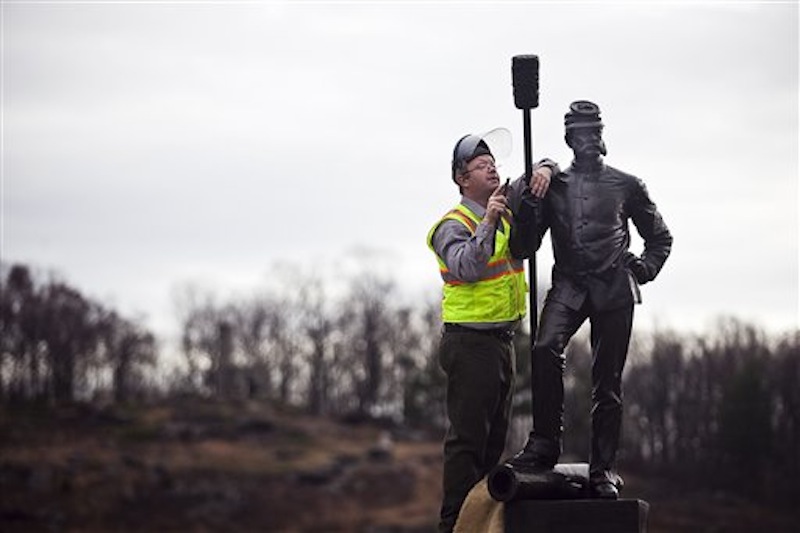 In this Monday Nov. 28, 2011, photo, National Park Service employee Brian Griffin, top, works on the newly restored bronze figure on top of the 4th New York Artillery Monument, Monday Nov. 28, 2011 in the Devil's Den area of Gettysburg National Park, Gettysburg, Pa. (AP Photo/The Evening Sun, Shane Dunlap)