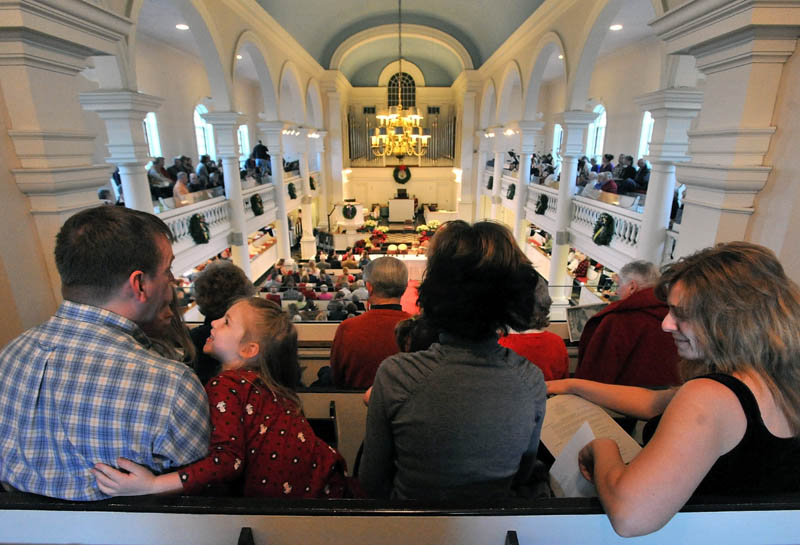 Sean Boyd, far left, has a moment with Lexi Delano, 5, as his wife, Mel, center and Christie Keller, far right, wait for the beginning of the Global Celebration of Christmas service at Lorimer Chapel at Colby College Saturday evening.