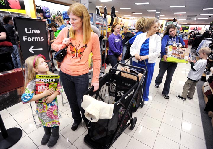 Emma Howe, left, looks up at her mother, Laurie Howe, as they wait in line at a Kohl's store in Owensboro, Ky., recently.