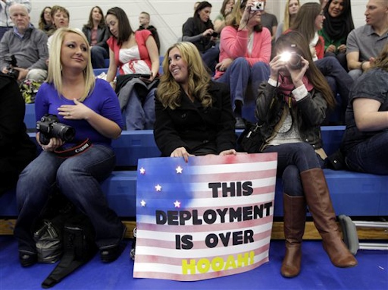 Brittney Davis, center, waits for her husband, U.S. Army Sgt. Donald Davis, Tuesday, Dec. 6, 2011, as she sits with Whitney Joy, left, who was waiting for her husband, Staff Sgt. Alex Joy, and their friend and personal photographer, Arielle Peace, right, as they wait for a welcome home ceremony to begin at Joint Base Lewis McChord in Washington state for soldiers who had been serving in Iraq. (AP Photo/Ted S. Warren)