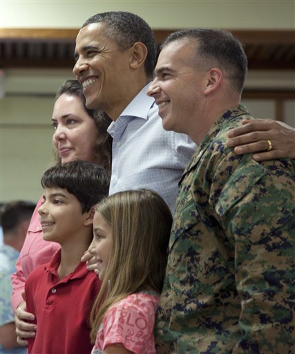 President Barack Obama poses with a military family during a visit to a Christmas dinner at Anderson Hall on Marine Corps Base Hawaii , Sunday, Dec. 25, 2011, in Kaneohe, Hawaii. (AP Photo/Carolyn Kaster)