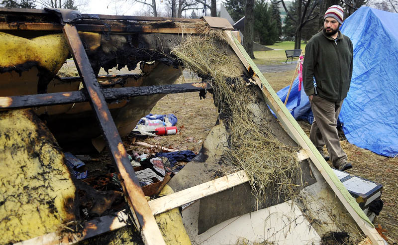 Occupy Augusta movement member Moss Stancampiano walks by a shelter Tuesday morning that burned the previous evening at the group's encampment at Capitol Park in Augusta. Police are investigating the arson, which did not injure anyone.