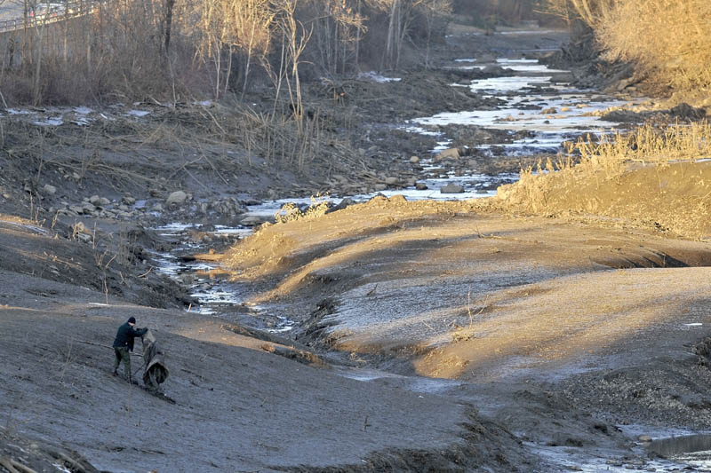 A searcher scours the emptied bed of the Messalonskee Stream along West River Road near the intersection of Kennedy Memorial Drive in Waterville this afternoon for a missing 20-month-old girl.