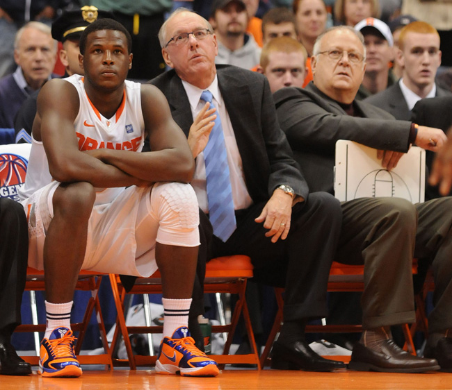 Syracuse basketball player Dion Waiter, left, sits on the bench beside head coach Jim Boeheim, center, and assistant coach Bernie Fine, right, during a game last year.