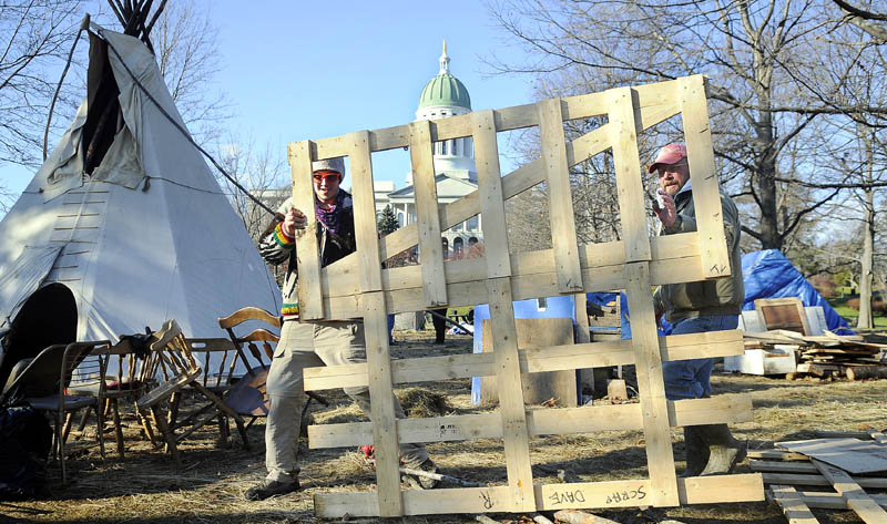 Occupy Augusta participant Lew Kingsbury, right, and Nick Messier carry a tent platform Thursday from Capitol Park in Augusta.