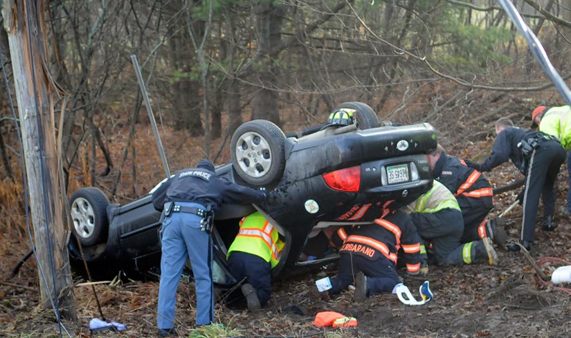 Staff photo by Andy Molloy ROLL OVER: Police and firefighters extricate a woman who was trapped in a car that rolled over this morning on the Hallowell Litchfield Road in West Gardiner. The vehicle left the road and snapped a utility pole around 8:30 a.m., according to Kennebec County Sheriff's Deputy Aaron Moody, pinning the driver for over half an hour. Several accidents were reported across Kennebec County, police said, as drivers encountered icy road conditions during the morning commute. The driver was flown to a trauma center for evaluation, Moody said.