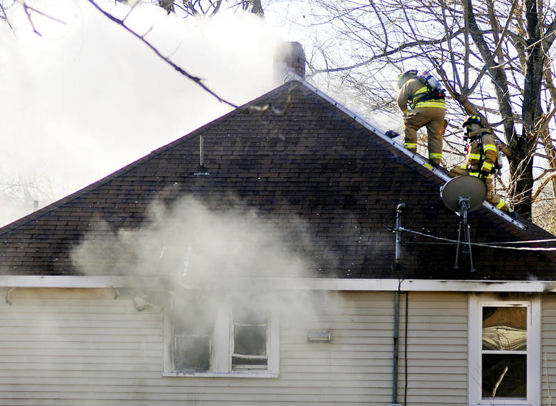 Firefighters ventilate the roof of a Winthrop house that burned on Tuesday.
