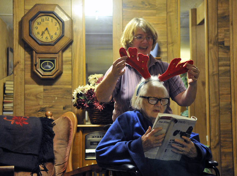 Staff photo by Michael G. Seamans Cheryl places Christmas antlers on her mother Alice before bed time at home in Industry on December 8, 2011. There are plenty of cheerful moments for Alice who is still able to communicate with her family. She just needs reminders as to where she is and what is going on at times. Larry describes caring for a dementia patient as much like caring for a child. Sometimes you need to read her reactions to figure out what her needs are at times.