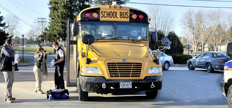 An ambulance attendant speaks with a bus driver outside her bus after a car collided with the rear of the bus at a five-way intersection in Waterville on Thursday. The children were checked and there were no injuries reported.