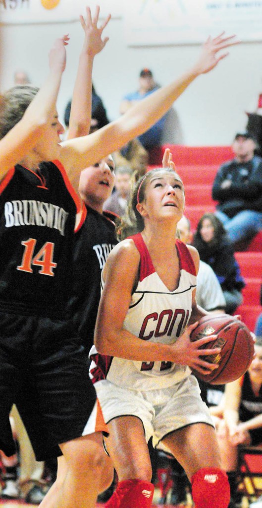 LOOKING FOR AN OPENING: Cony High School’s Josie Lee goes up for a shot under the defense of Brunswick’s Liz Faulkner during the season opener Friday night in Augusta.