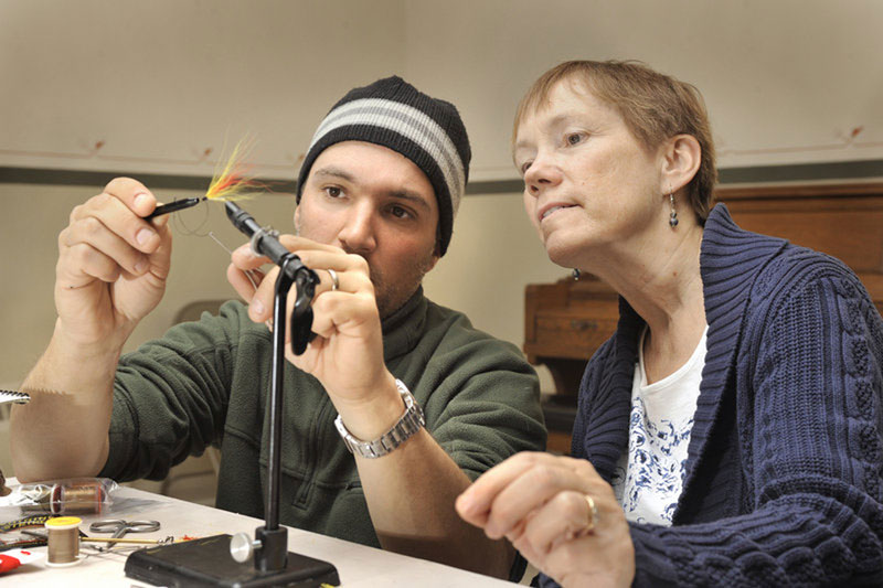 LIKE THIS: Greg Bostater, a Maine guide and class organizer, helps to assemble a Mickey Finn during a recent fly tying class. “Nothing is quite like being in a class and getting that sense of community,” he says.