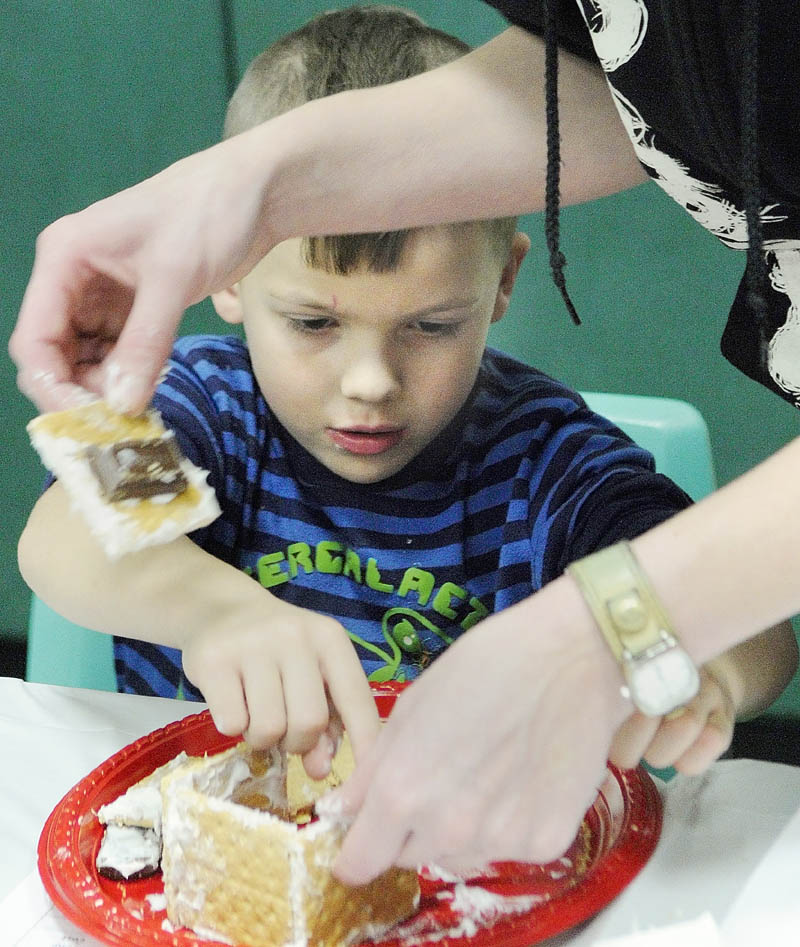 STICKY ENGINEERING: Kindergartener Trysten Legassie and his mother, Samantha Cushing, build and decorate a train from graham crackers, frosting and candy during a Math Mania event Thursday at Laura E. Richards School in Gardiner. About 150 parents and kids attended the event, which featured a pizza dinner after math games and was held to help support math concepts the students have been learning, according to Principal Karen Moody.
