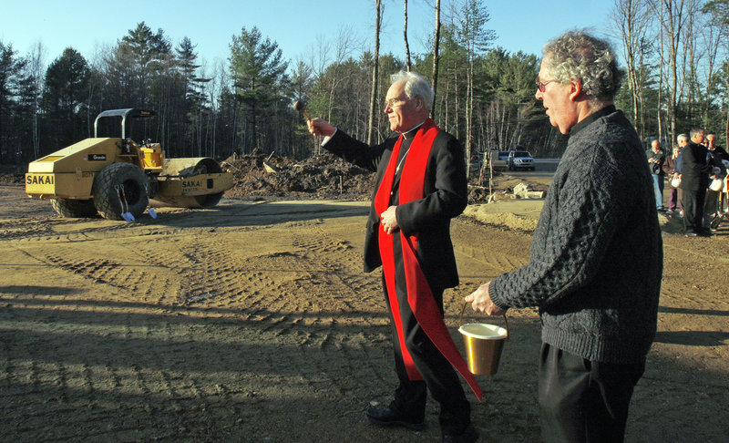 BLESSING: Bishop Richard Malone sprinkles holy water Wednesday at the site of a new Roman Catholic church in South Berwick. At right is Rev. Joseph Cahill, the parochial vicar for the parish.