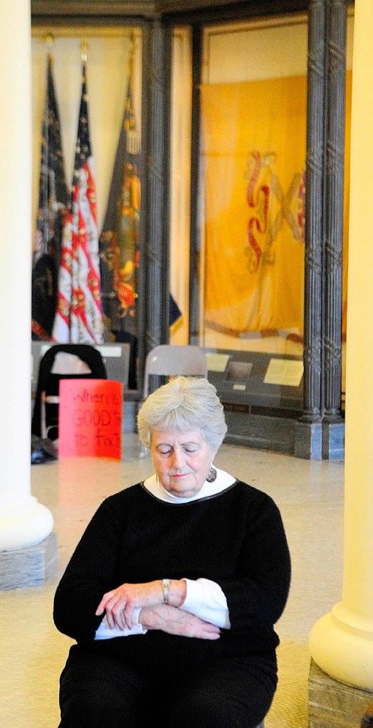 SOLEMN MOMENT: Denise Dreher, of Biddeford, prays in the State House’s Hall of Flags on Friday in Augusta. The Maine Council of Churches held a prayer vigil up the hallway from where a legislative committee held a three-day hearing on the Department of Health and Human Service’s supplemental budget.