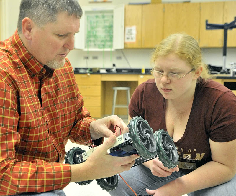 Science teacher Jeff DeJongh, left, and student Brittany Manson check the wiring on a malfunctioning robot on Thursday morning at Cony High School in Augusta.