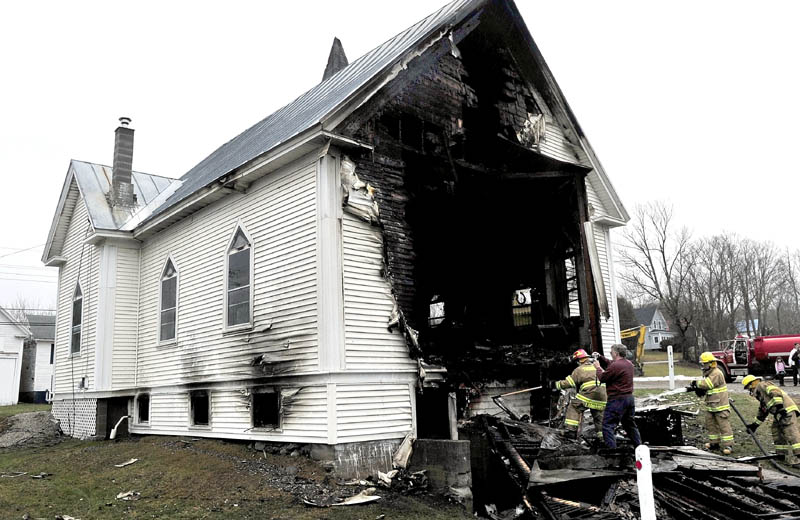 Firefighters extinguish smoldering wood as Stu Jabobs of the state fire marshal’s office photographs the scene near the back side of the Thorndike Congregational Church after fire destroyed the century-old church early Wednesday. Investigators determined the cause was an electrical malfunction. Church deaconess Patty Banker later said the church will be rebuilt.