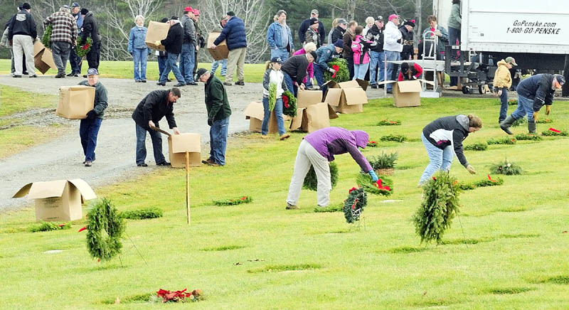 A SIMPLE GESTURE: Volunteers unload the truck and start to lay wreaths on markers Saturday morning at the Maine Veterans’ Memorial Cemetery on Mount Vernon Road in Augusta. Volunteers with the Wreaths Across America project also laid wreaths on graves there and at Togus National Cemetery.