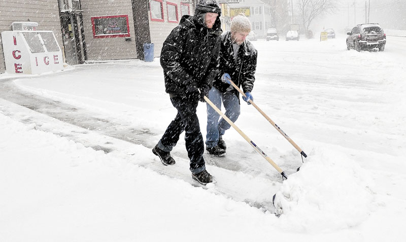 TEAMWORK: Dave Huntington, left, and Brad Hayden shovel snow off the parking lot at Jokas store in Waterville on Thursday.