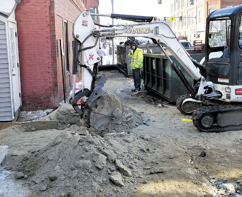 DIG IT: An excavator operator with E.L. Vining & Sons on Monday digs up the sidewalk where a water main pipe broke. The water filled the basement of TD Bank and Trask Jewelers in downtown Farmington, causing extensive damage to both businesses.