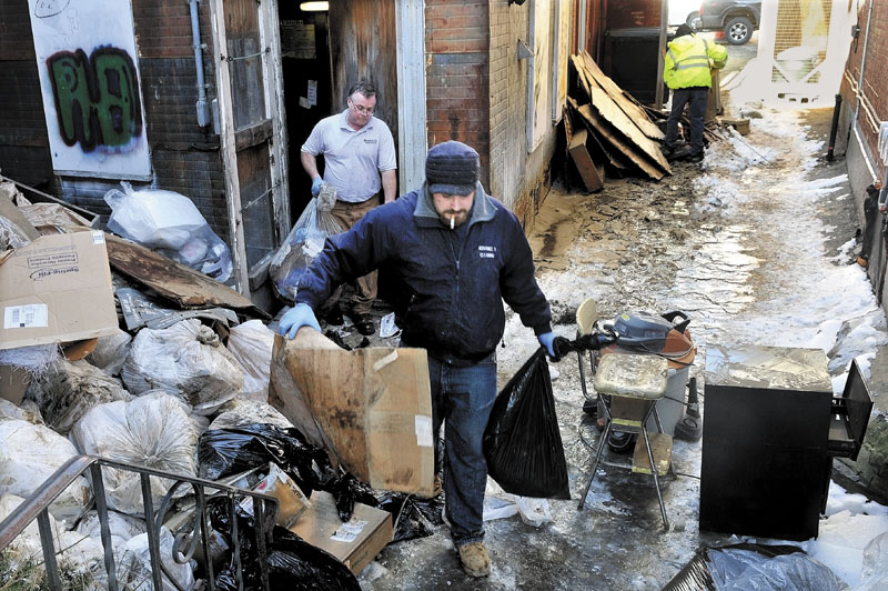 CLEAN UP: Workers carry water-soaked debris through an ice-covered alley behind Trask Jewelers in Farmington on Monday while cleaning up after a water main break.