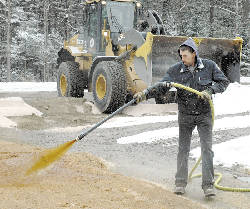 GREEN SALT: Bob Corrigan of the Skowhegan Highway Department sprays Ice B’Gone, a road de-icer made from high-sugar beet molasses, on road salt at the town sand-and-salt yard recently. Road Commissioner Greg Dore hopes it will save money on winter road budgets.
