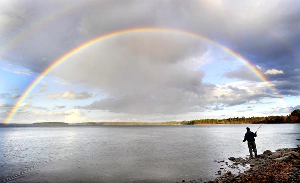 In this 2010 photo, fly fisherman Stephen Sparaco is framed by a rainbow as skies clear over Sebago Lake in Standish.