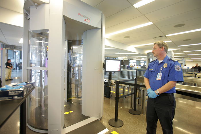 TSA employee Dale Tucker stands near one of three new passenger screening devices in the security checkpoint area at jetport today. The devices screen for metallic and nonmetallic items using electromagnetic waves.
