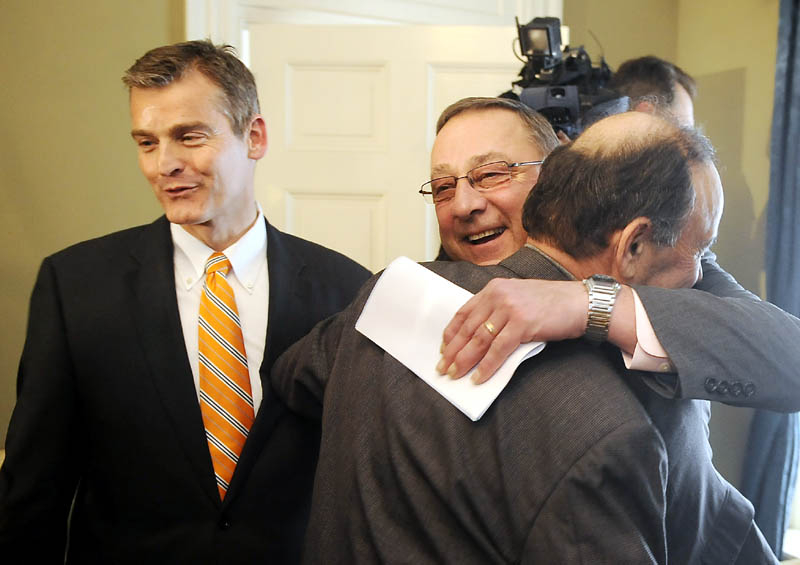 KEEPS ON GIVING: Gov. Paul LePage hugs Bill Alfond on Monday during a ceremony in Augusta after announcing that the Harold Alfond Foundation will give $10.85 million to the Maine Community College System and to the Good Will-Hinckley school in Fairfield. Alfond was joined by Good Will-Hinckley President Glenn Cummings, left, to unveil the donation that will enable Maine Community College System to expand the capacity of Kennebec Valley Community College in Fairfield by an additional 1,500 to 2,000 students through the purchase of 600 acres and 13 buildings at Good Will-Hinckley.