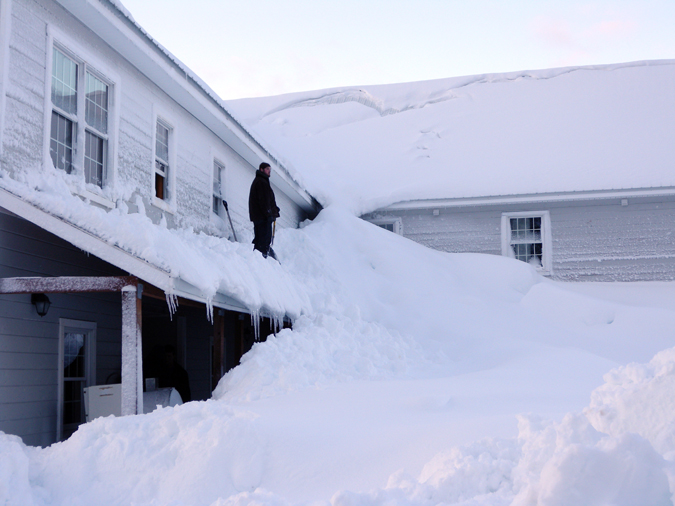 A Jan. 7, 2012, photo provided by the Alaska Division of Homeland Security and Emergency Management shows a man standing on a house buried in snow in the fishing town of Cordova, Alaska.