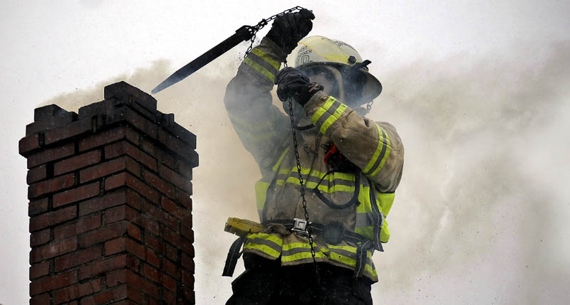 West Gardiner Fire Chief Chris McLaughlin pulls a chain up a chimney on fire Thursday in West Gardiner. Firefighters from West Gardiner and Gardiner worked for an hour at extinguishing the blaze on High Street.