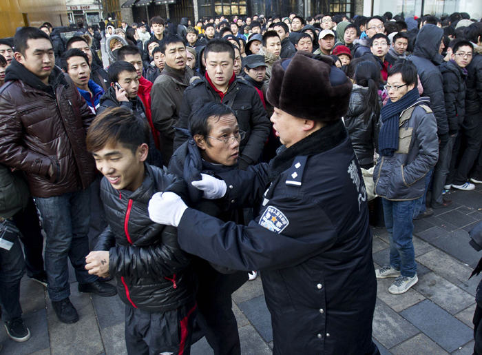 A policeman drags away people who refused to leave the Apple Store in Beijing today after Apple closed the store.