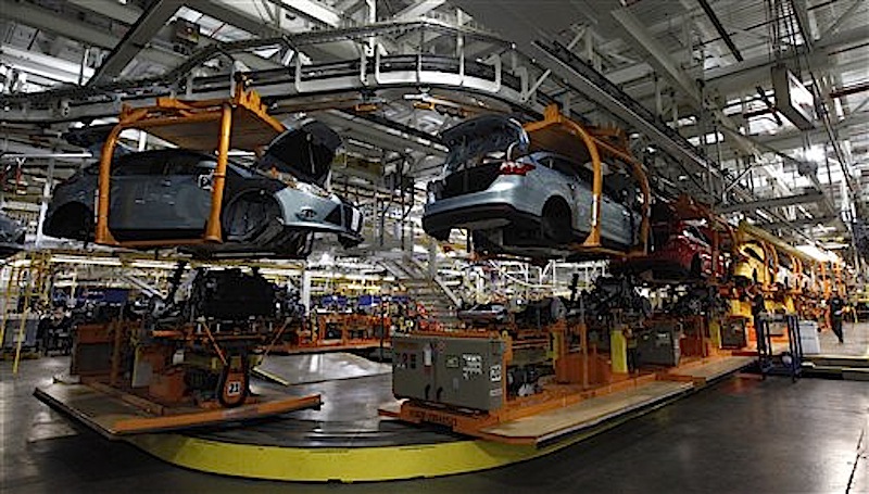 In this Dec. 14 photo, Ford Focus vehicles move on the assembly line at the Ford Michigan Assembly plant in Wayne, Mich. U.S. factories roared to life in December, creating sharply more goods to meet strong demand for business equipment, materials, vehicles and energy. (AP Photo/Paul Sancya)