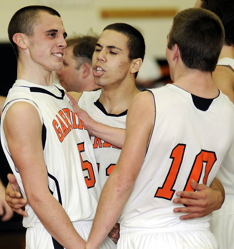 VICTORIOUS: Gardiner’s Jake Palmer, left, Alonzo Connor, center, and Justin Lovely celebrate after beating Winslow High School with 2.6 seconds left Tuesday in Gardiner.