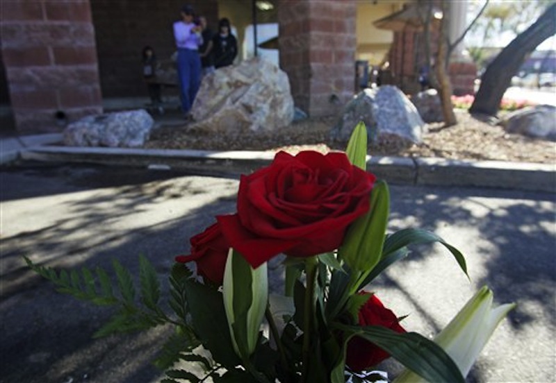 People gaze at a small memorial plaque on a rock at the Safeway market on Saturday, Jan. 7, 2012, to commemorate the victims of the mass shooting on Jan. 8, 2011, in Tucson, Ariz. The one-year anniversary of the shooting of Rep. Gabrielle Giffords in the parking lot of the grocery store is Sunday. Arizona is marking the event with a series of events, including community-wide bell-ringing at the moment of the attack, speeches on behalf of the victims, and an evening candlelight vigil that Giffords will attend. (AP Photo/Arizona Daily Star, Rick Wiley)