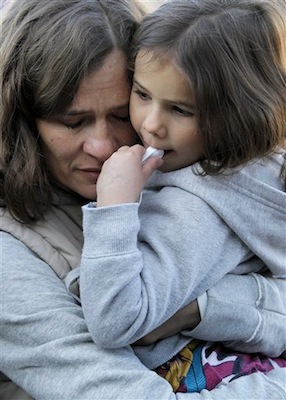 Ina Menzl, left, hugs her daughter, 4-year-old Rebecca Kraft, on Sunday outside the Safeway grocery store where U.S. Rep. Gabrielle Giffords, D-Ariz., was shot one year ago during a shooting spree that left 6 dead and 13 wounded, including Giffords. (AP Photo/Matt York)