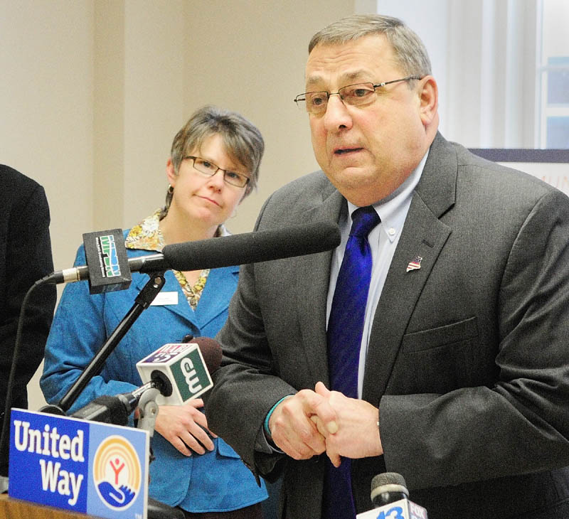 United Ways of Maine chairman Lisa Laflin, of the Tri-Valley United Way in Farmington, left, listens to Gov. Paul LePage during a news conference on Friday in Augusta.