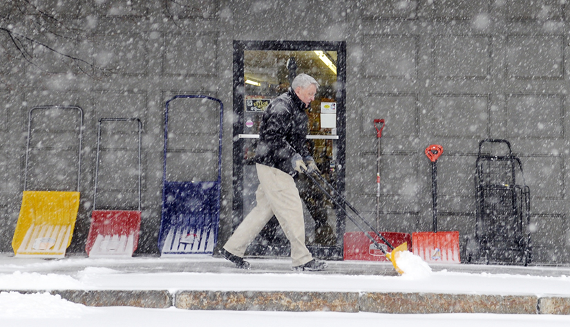 INVENTORY: Bill Harvey shovels snow Thursday from the walk in front of his Gardiner business, Harvey's Hardware. Several inches of snow is forecast.
