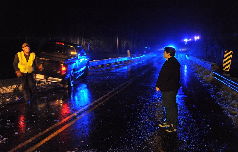 Amity Watts, right, watches as a wrecker pulls her 2008 Dodge Ram from the bridge railing on Unity Road near Benton Friday night. Eight cars were reported to have been off the road with in a quarter mile stretch of road as driving conditions became dangerously icy.
