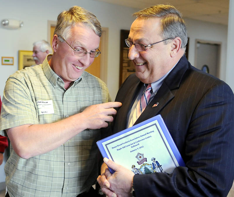 Gov. Paul LePage, right, confers Monday with Phil Bibeau of the Wood Products Manufacturers Association of Westminster, Mass., before addressing a gathering of the Maine Wood Products Association in Hallowell.