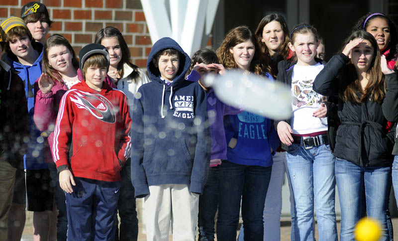 Maranacook Community Middle School students watch a bottle of frozen water, center, and a ball drop in tandem on Monday during a physics lesson at the Readfield school. A Central Maine Power crew hoisted several items, including pumpkins, up in a bucket and dropped them at the school to test Newton's law of motion. The students watched eggs, vegetables and several balls hit the pavement together.